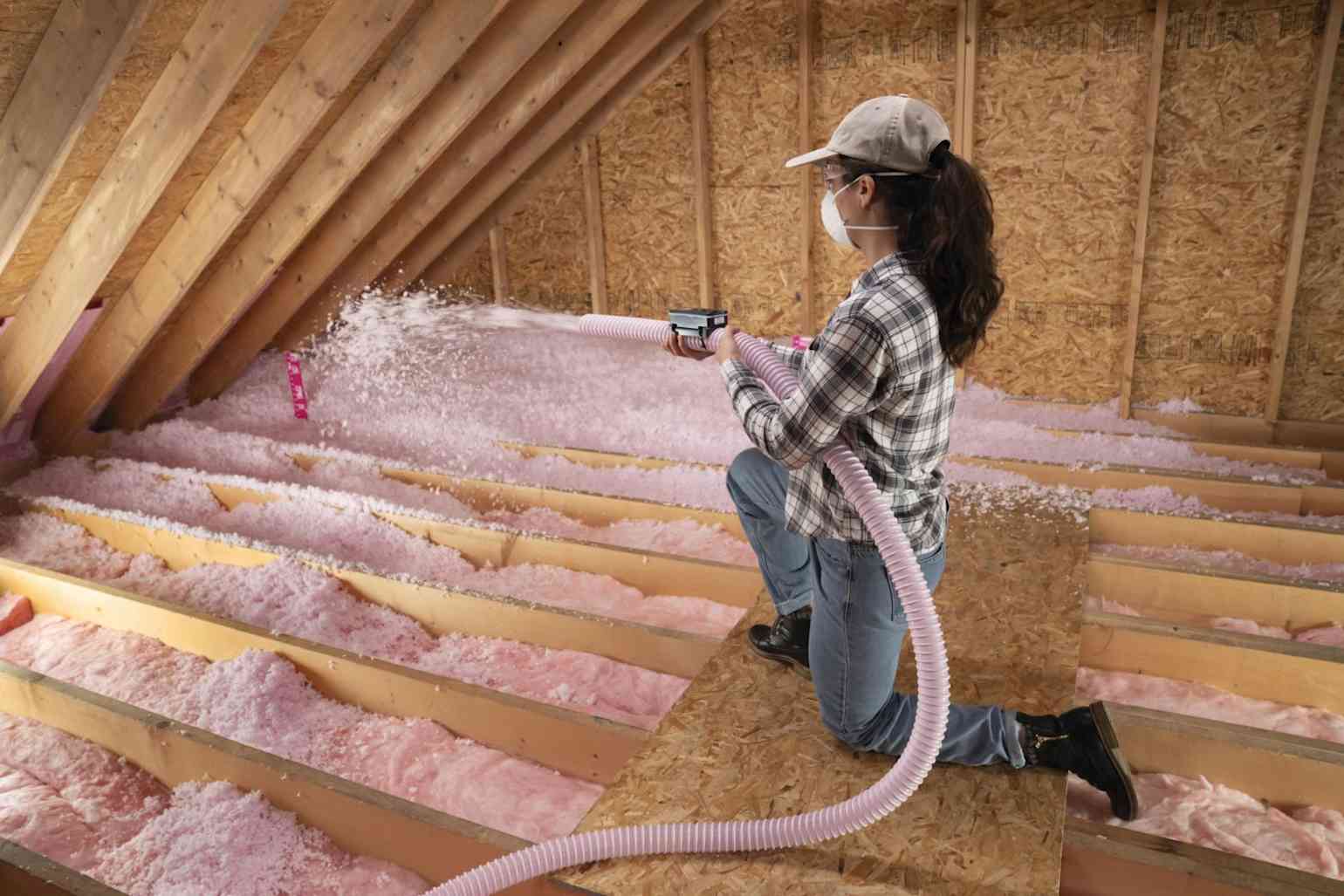 Worker blowing Owens Corning PINK NEXT GEN insulation in an attic